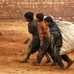 a group of young boys walking down a dirt road