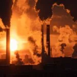 Air pollution and global warming. Smoking chimneys of thermal power plant at sunset in winter city