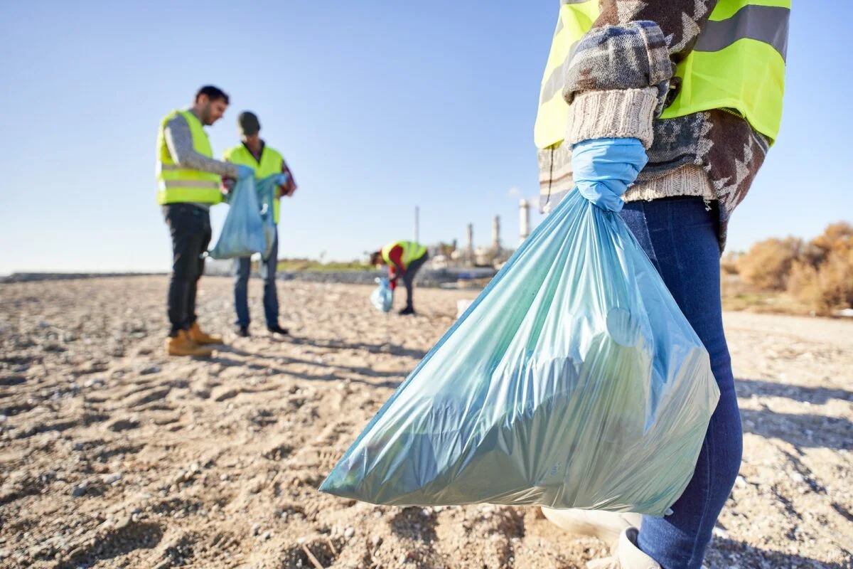 Cuidado del medio ambiente: Qué es, Importancia y Cómo Preservarlo Group portrait activists holding plastic waste. Blue garbage bag in foreground. Environmental care.
