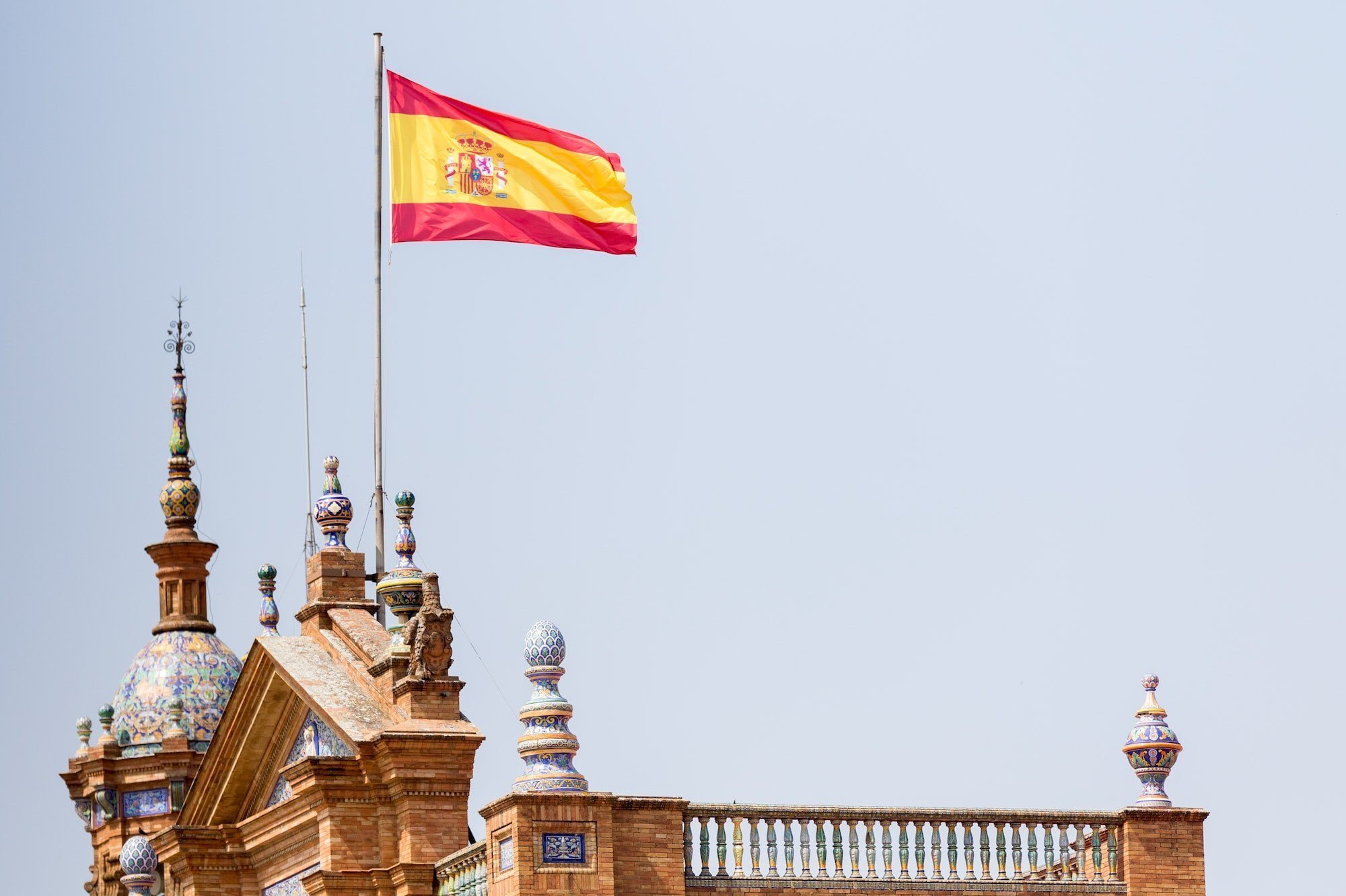 The flag of Spain flies over the building at the Plaza de España in Seville